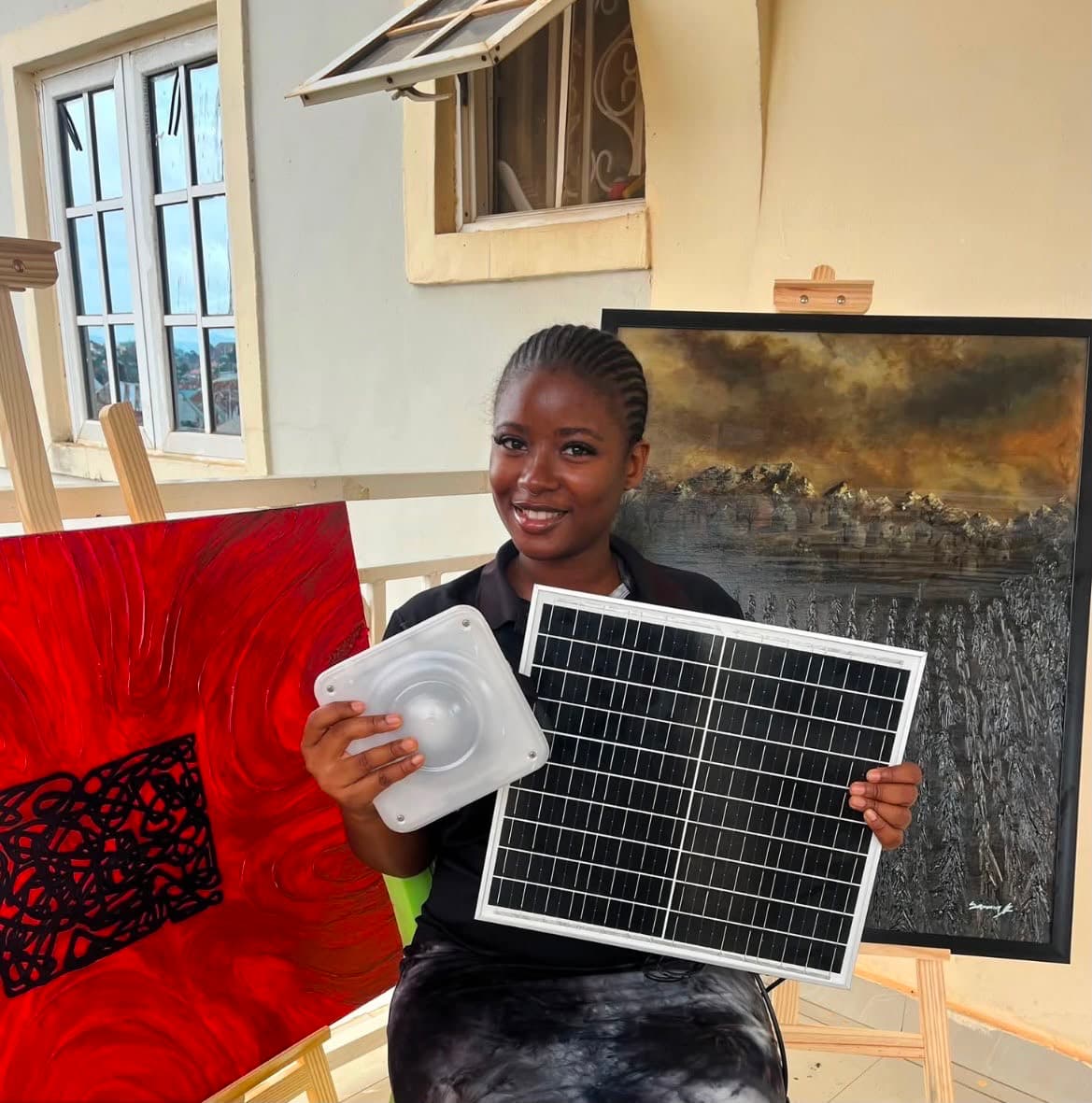 Young artist with a Quadloop solar kit in front of original paintings.